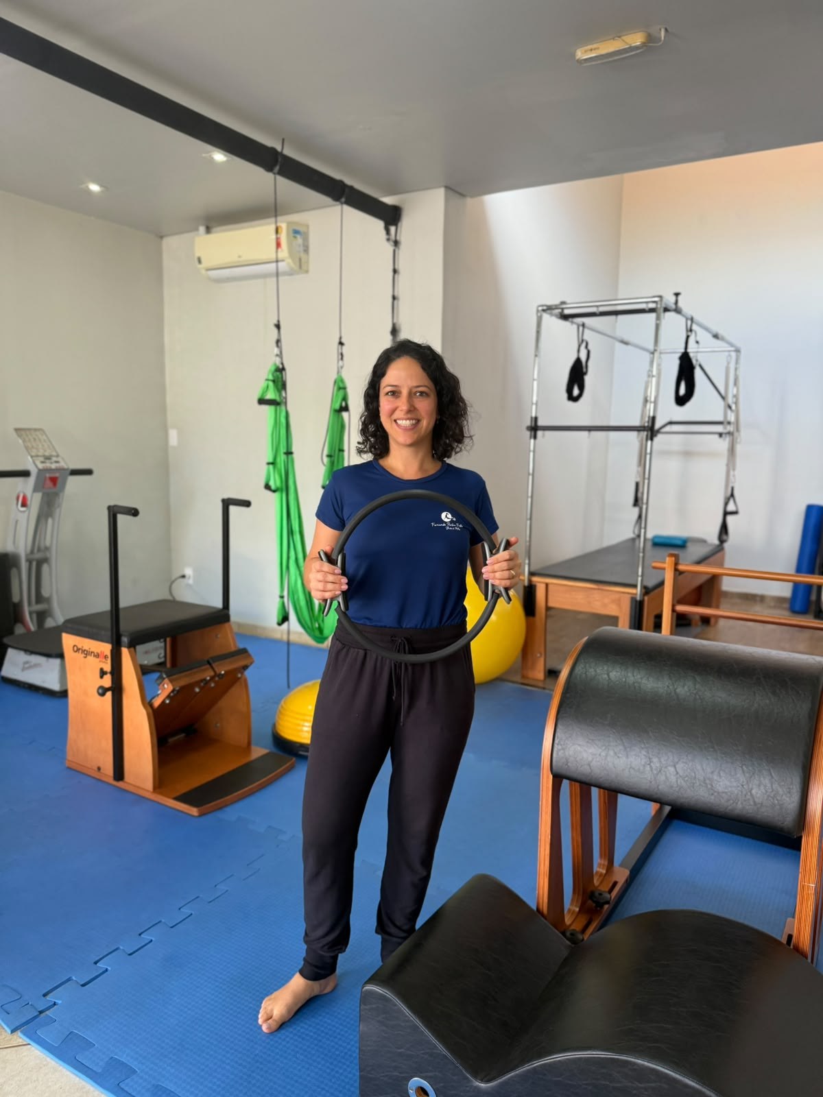 Fernanda Penha Frota no Studio de Pilates, com os equipamentos ao fundo